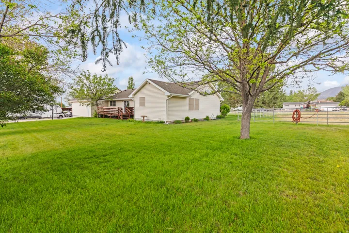 Expansive green lawn with mature trees and a rear deck