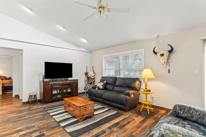 Living area featuring vaulted ceilings, wood-finish flooring, a ceiling fan, and recessed lighting