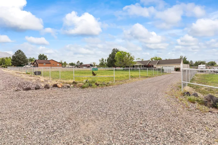 Gravel driveway accessing the property, featuring a fenced perimeter