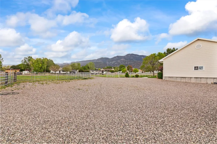 Expansive gravel lot with fencing, bordering a grassy area with additional fencing
