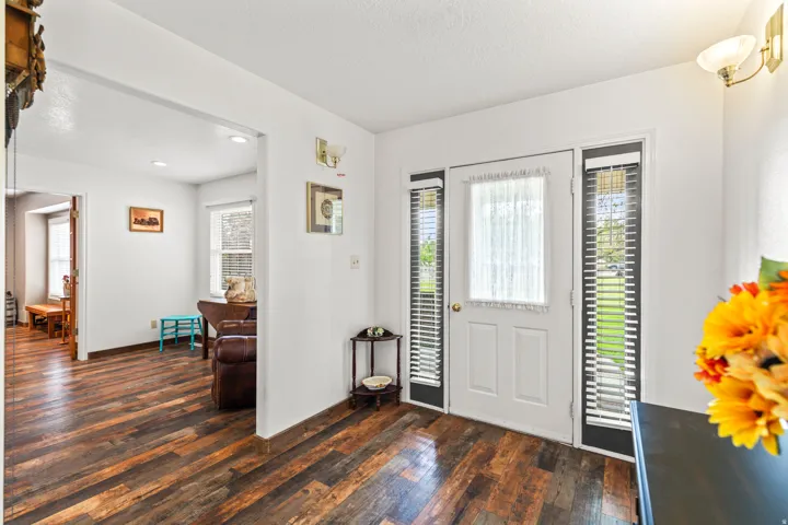 Entryway featuring wood-finish flooring, a white paneled door with curtain, and vertical side windows with blinds