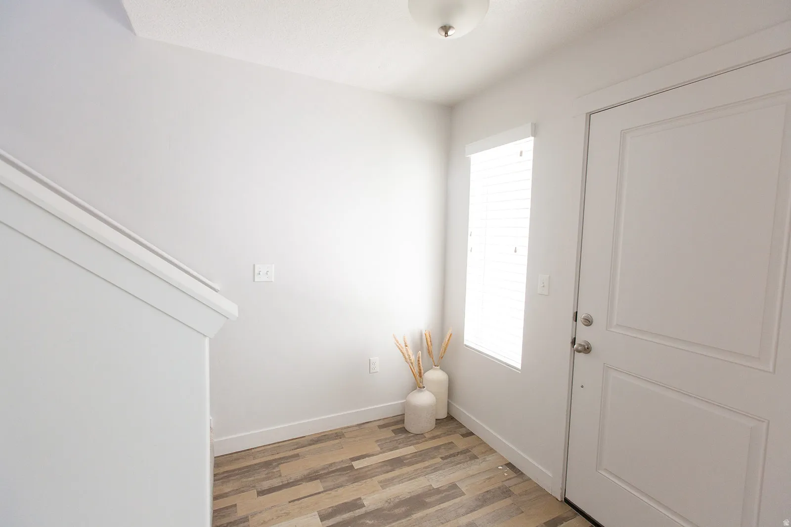 Entryway featuring a paneled door, wood-finish flooring, and a window with horizontal blinds