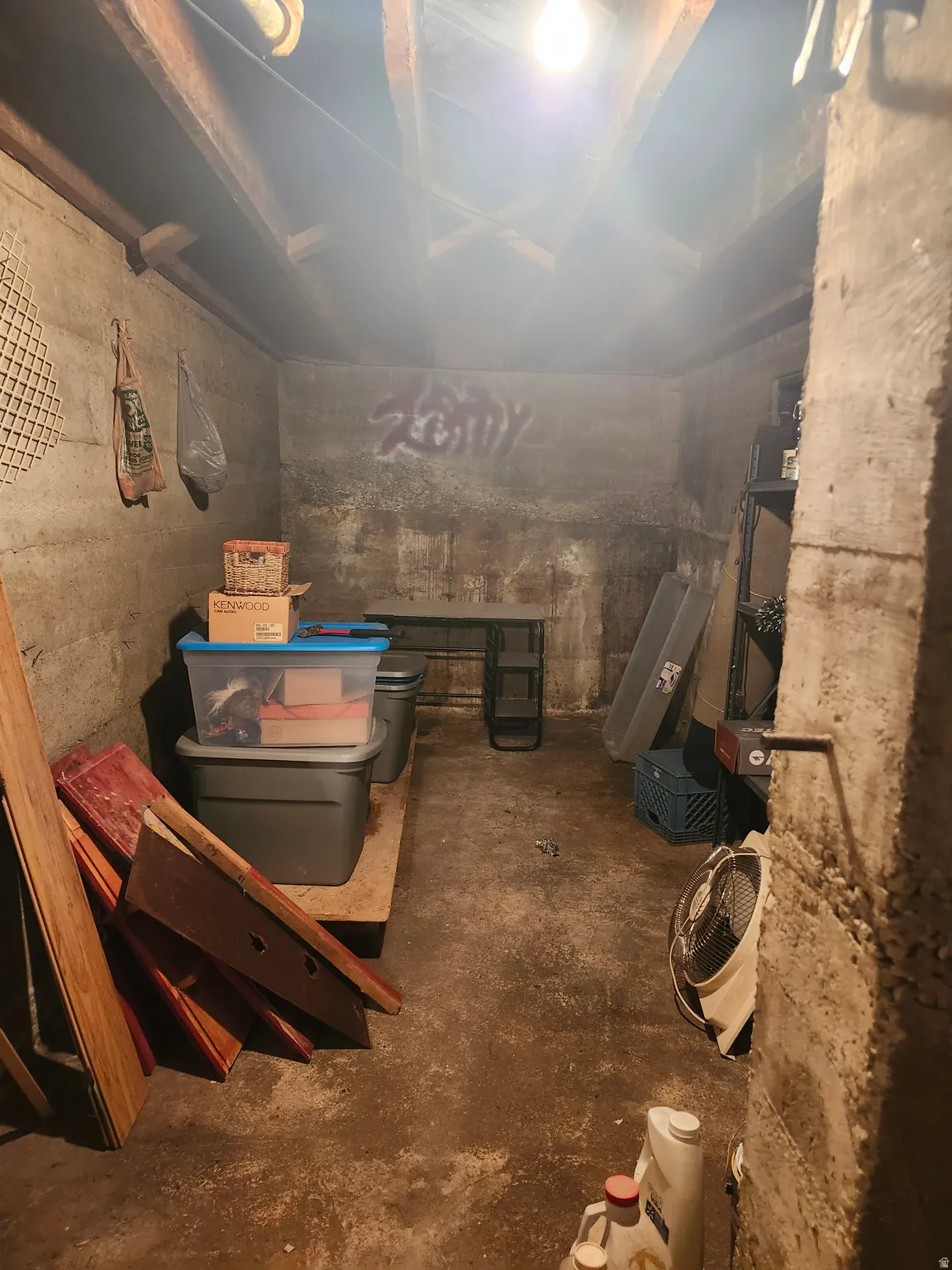 Unfinished basement featuring exposed wood ceiling joists and concrete walls