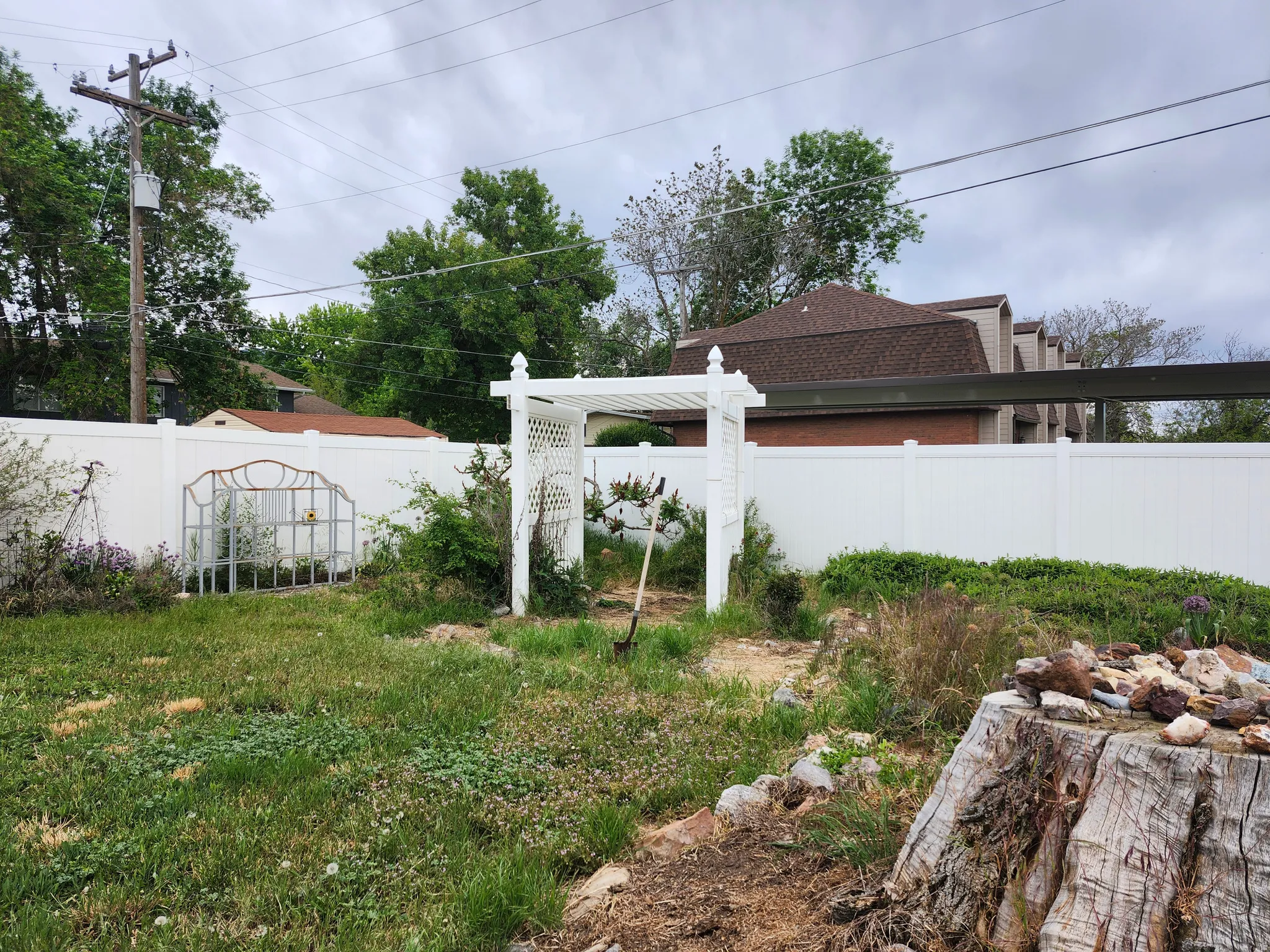 Fenced backyard featuring a white vinyl privacy fence, a decorative metal gate, and a white garden arbor