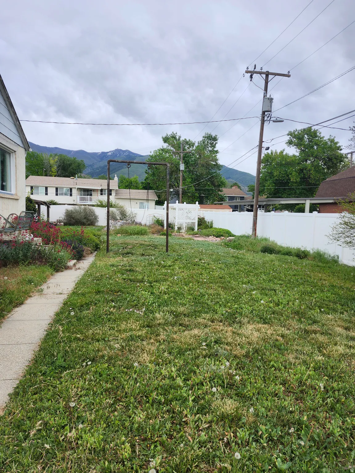 Expansive grassy yard with a concrete pathway and mature landscaping