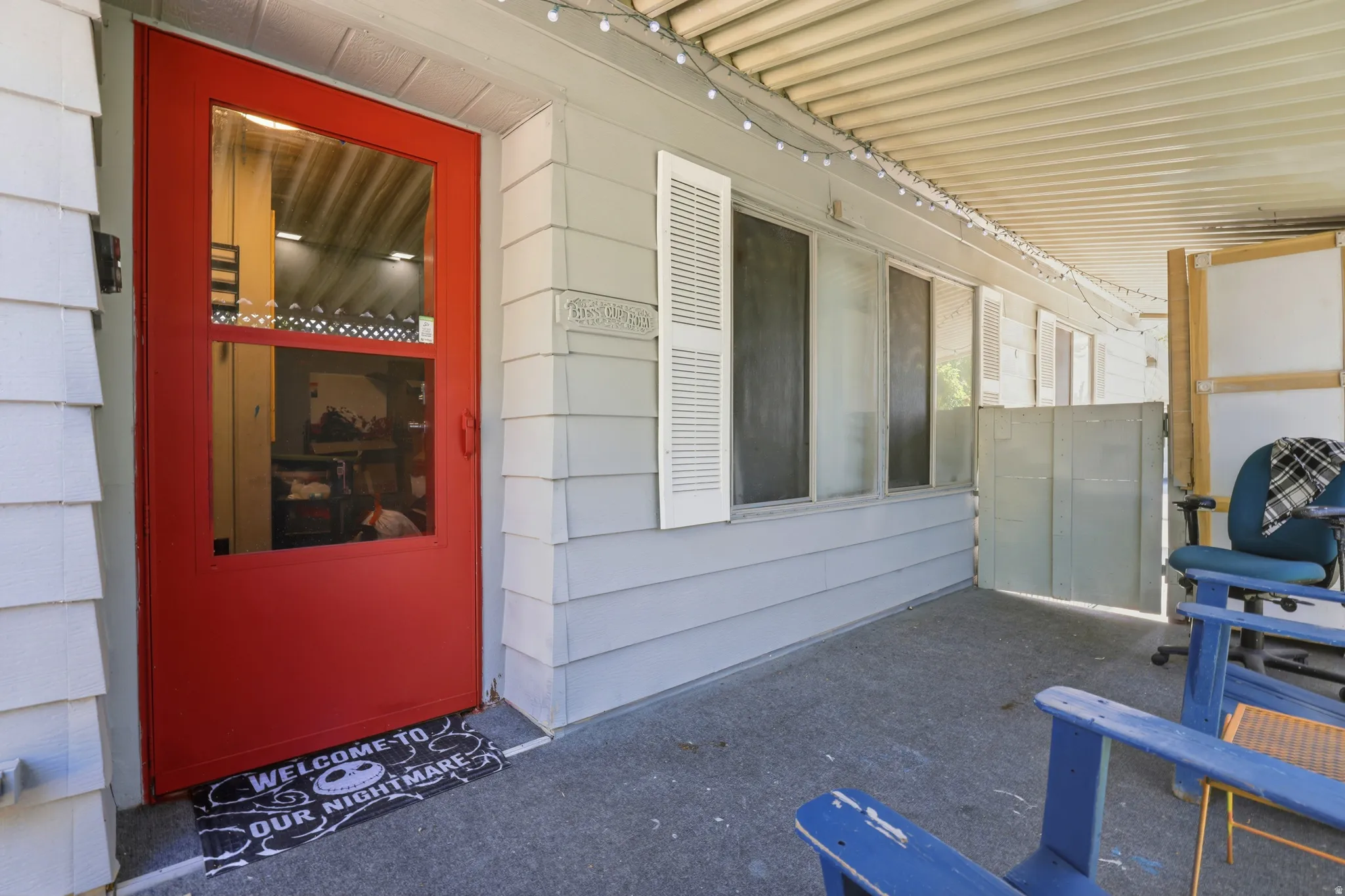 Covered porch entry featuring a red screen door, horizontal siding, and multiple windows