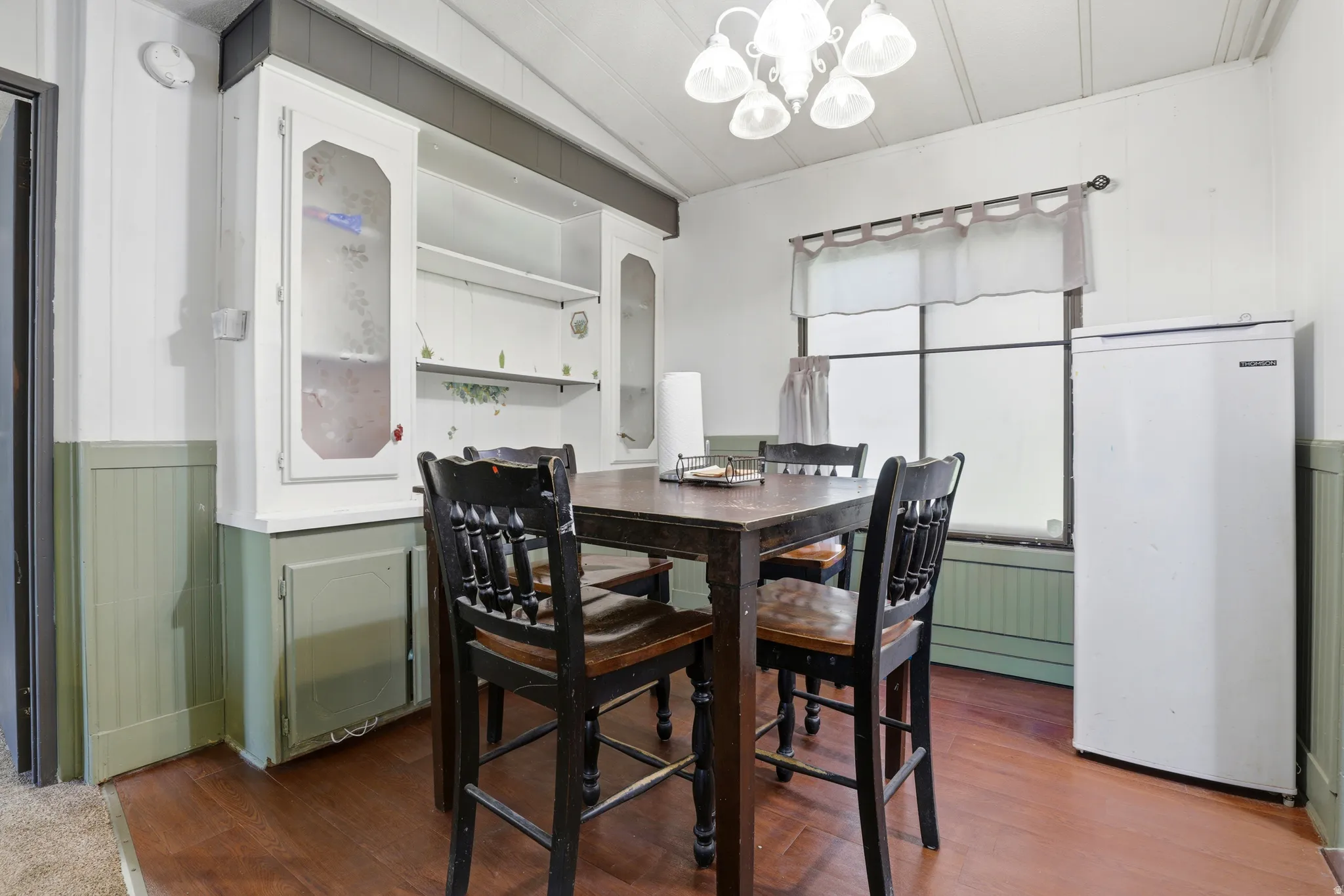 Built-in cabinetry with glass-front display, overhead lighting fixture, and wood-finish flooring