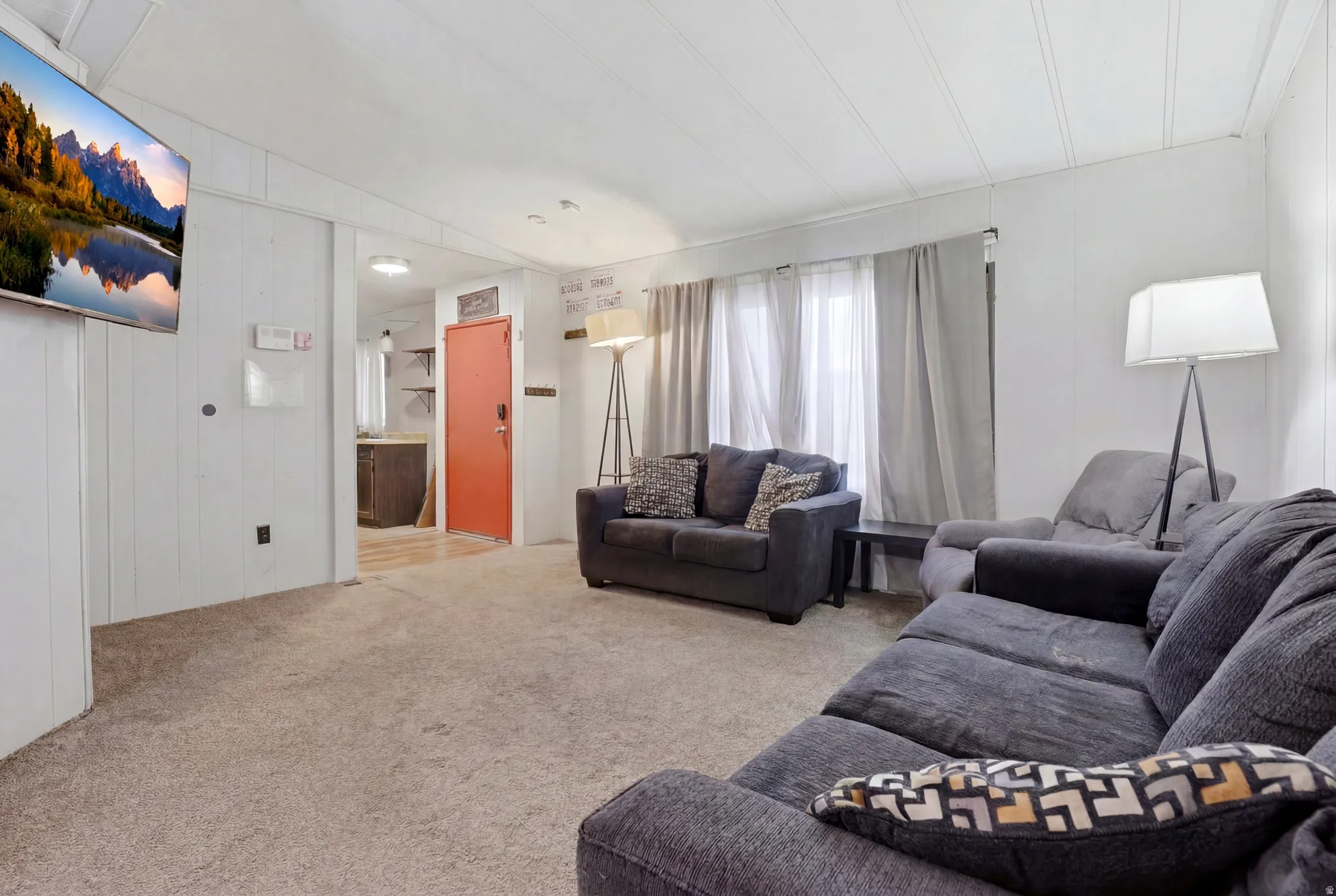 Living area featuring light-toned carpeting and vertical paneling