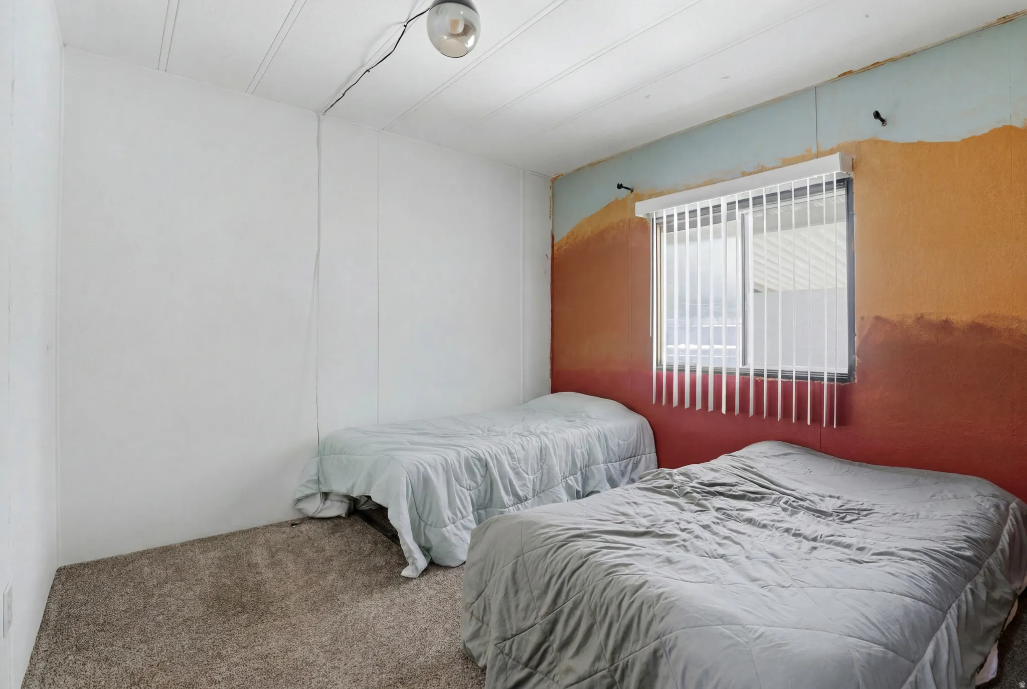Carpeted room featuring a window with vertical blinds, a wall-mounted light fixture, and painted walls