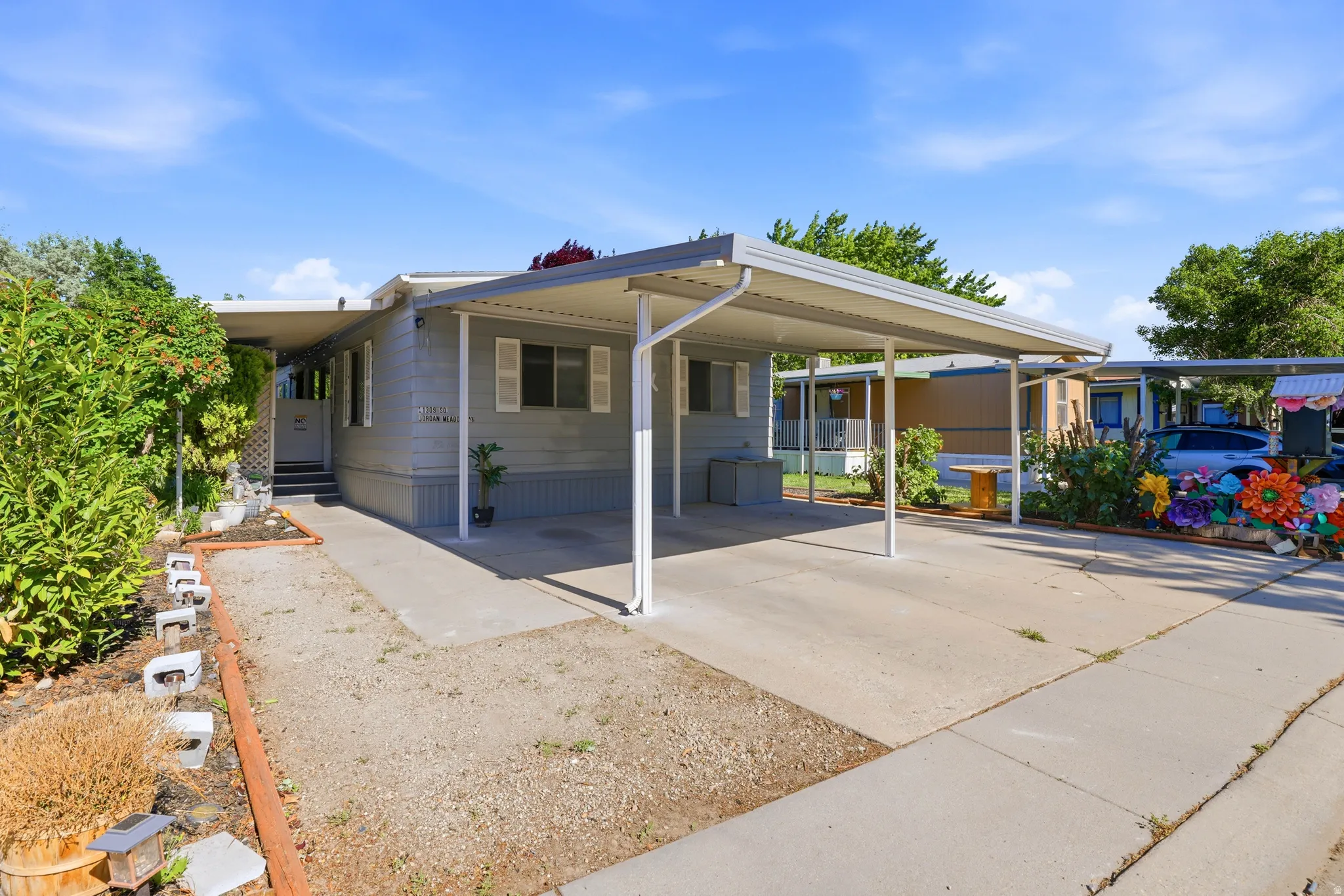 Exterior featuring light gray siding, white window shutters, a covered carport, and a concrete driveway