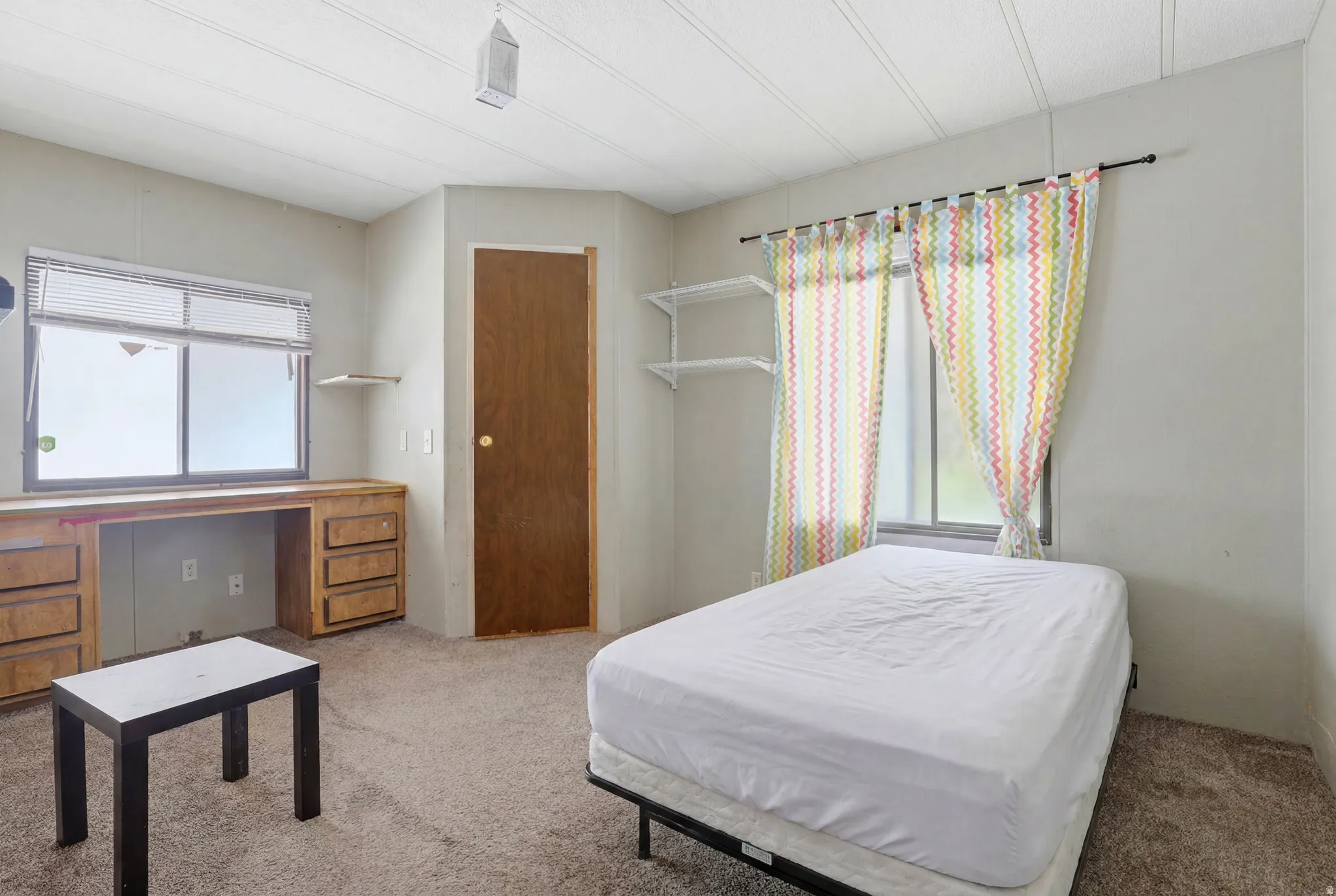 Carpeted room with a built-in wooden desk featuring multiple drawers