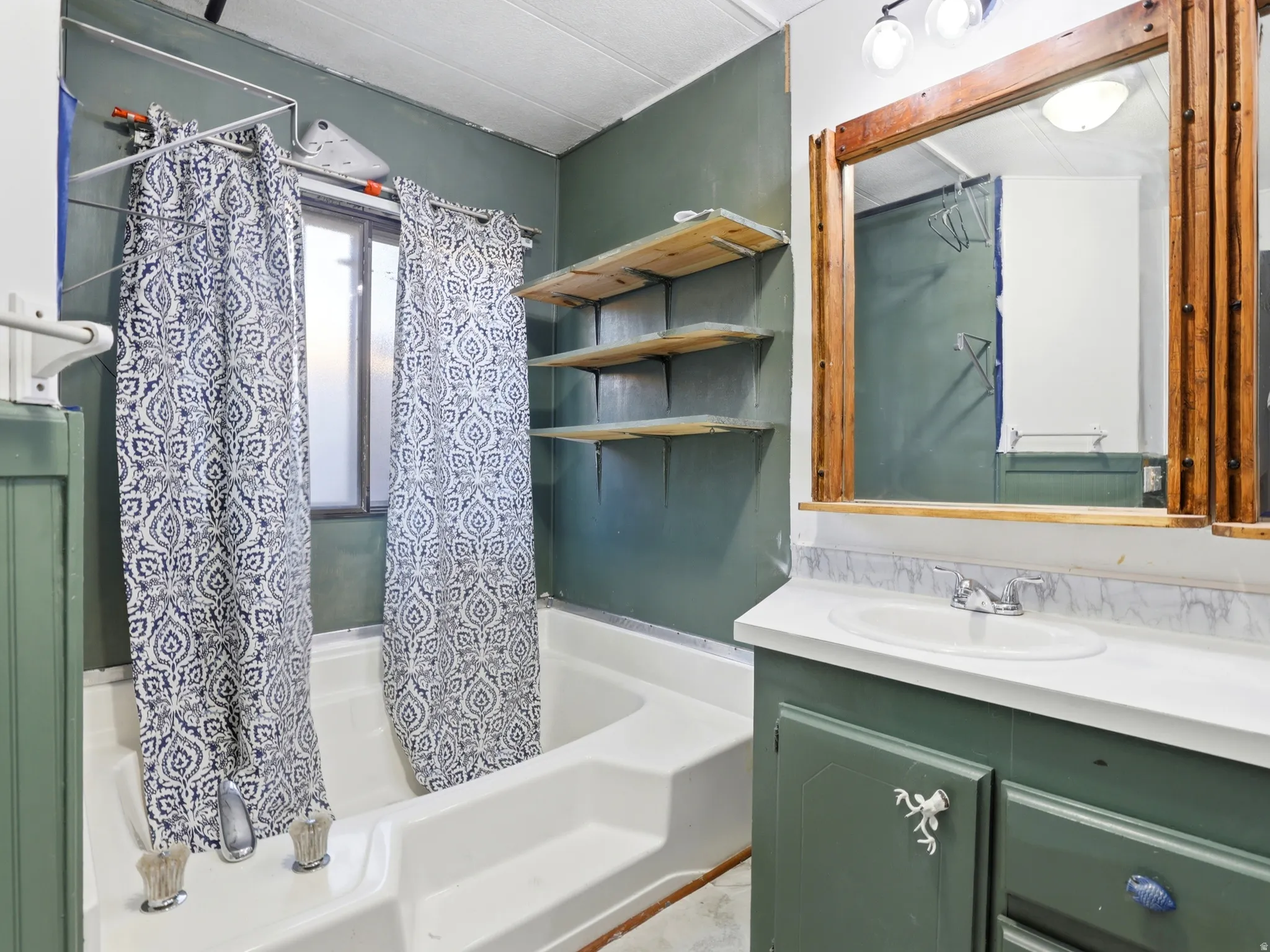 Bathroom featuring a double vanity with an integrated sink, a large framed mirror, a window, and open shelving