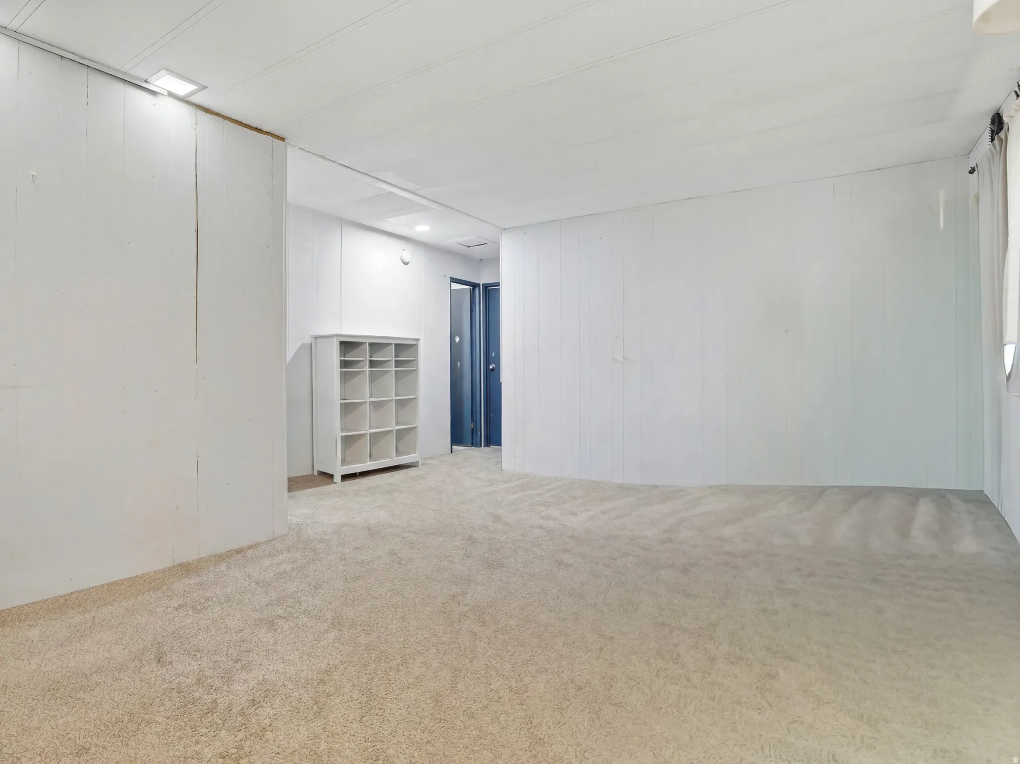 Carpeted interior space with white paneled walls and a white ceiling