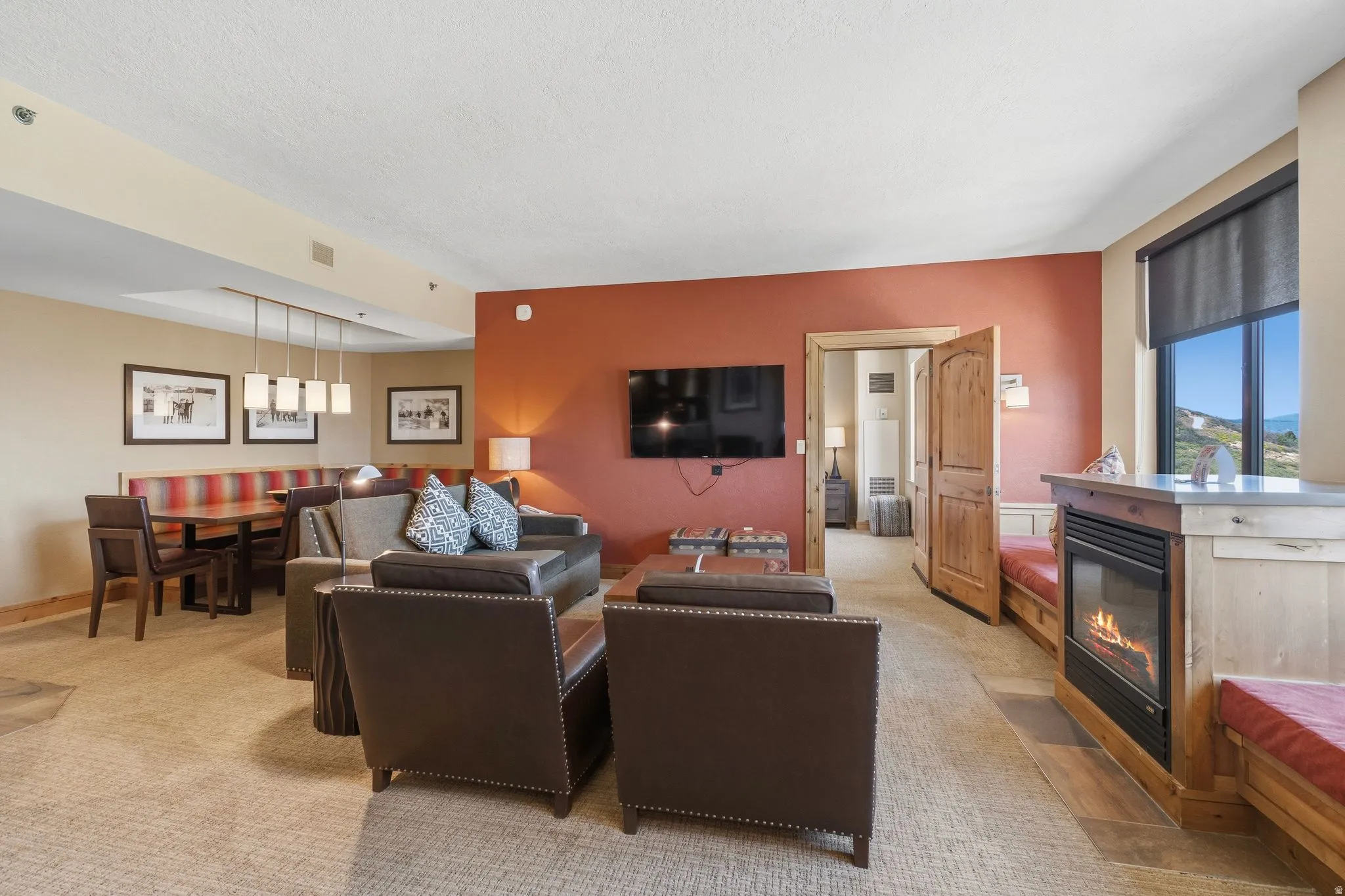 Open-concept living area with a stone-surround fireplace, built-in window seating, and carpeted flooring