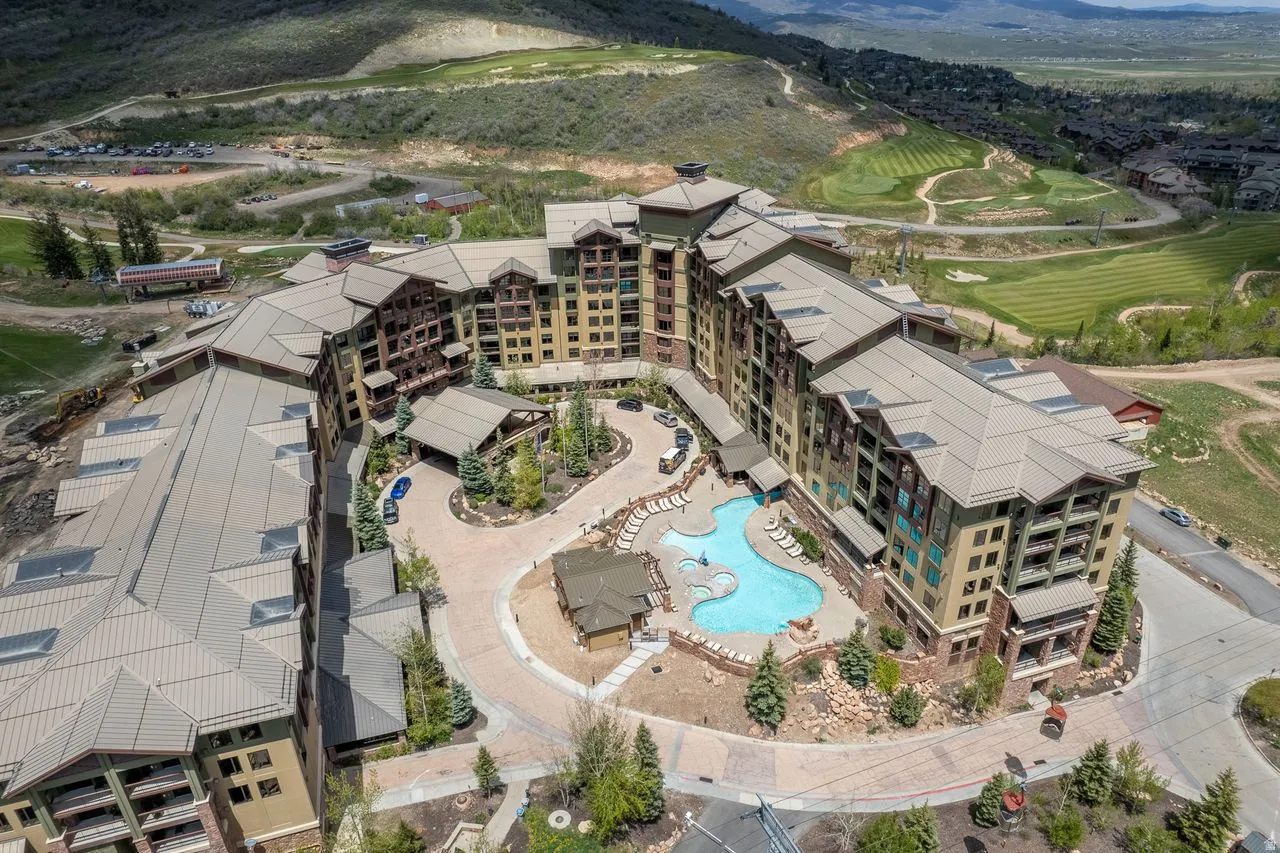 Expansive resort-style development featuring multiple buildings with private balconies, an outdoor pool with integrated spa, and mature landscaping