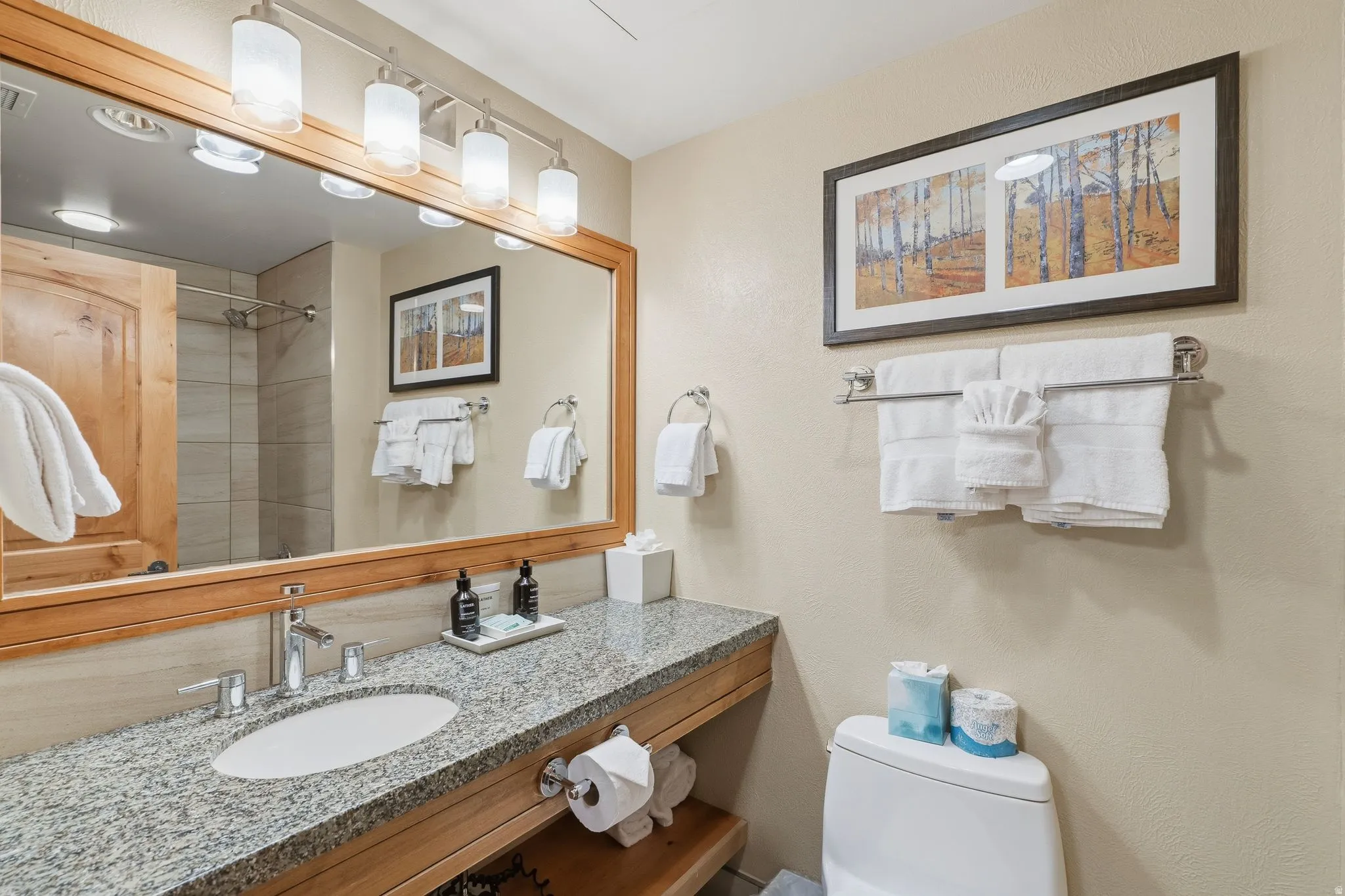 Spacious vanity featuring a granite-finish countertop, undermount sink, and wood-finish cabinetry