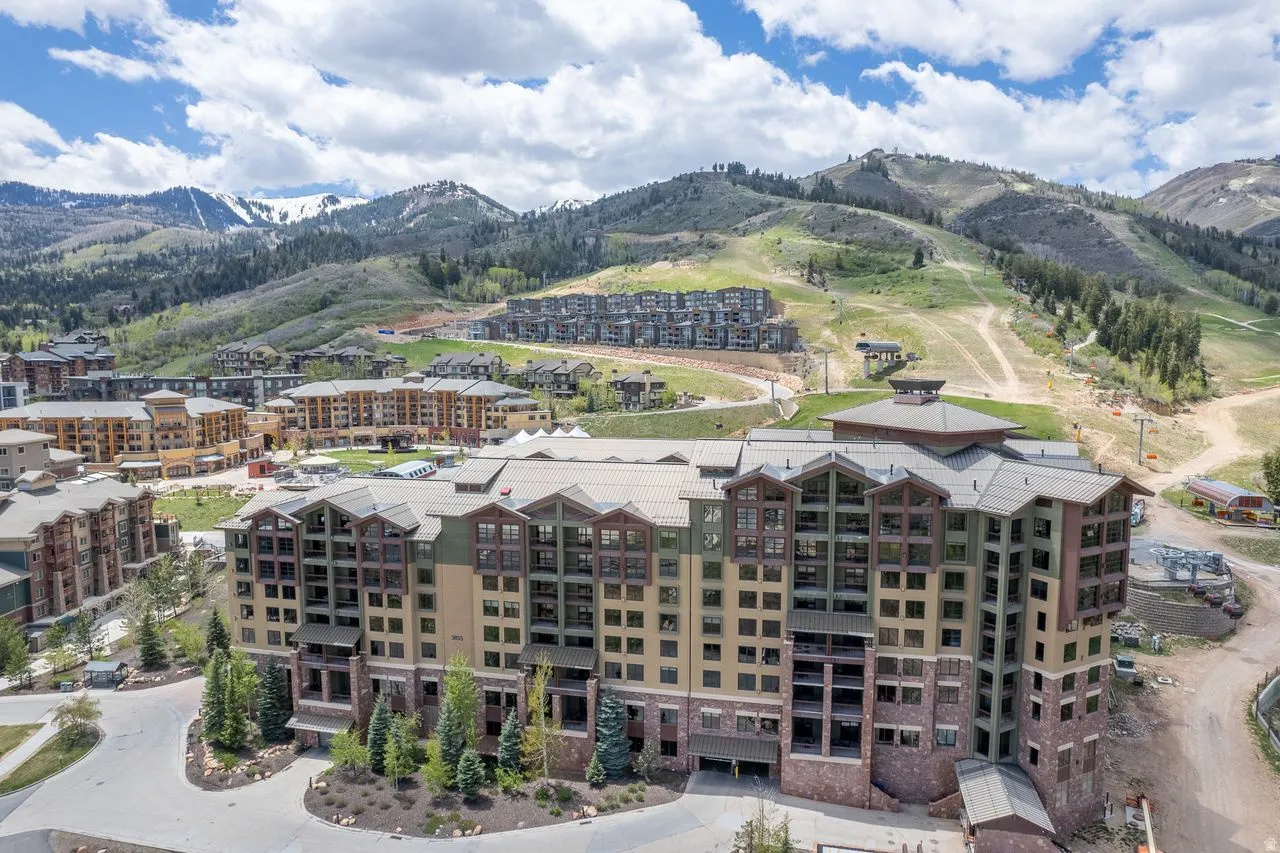 Multi-story building featuring stone and siding exterior, multiple balconies, and a distinctive roofline