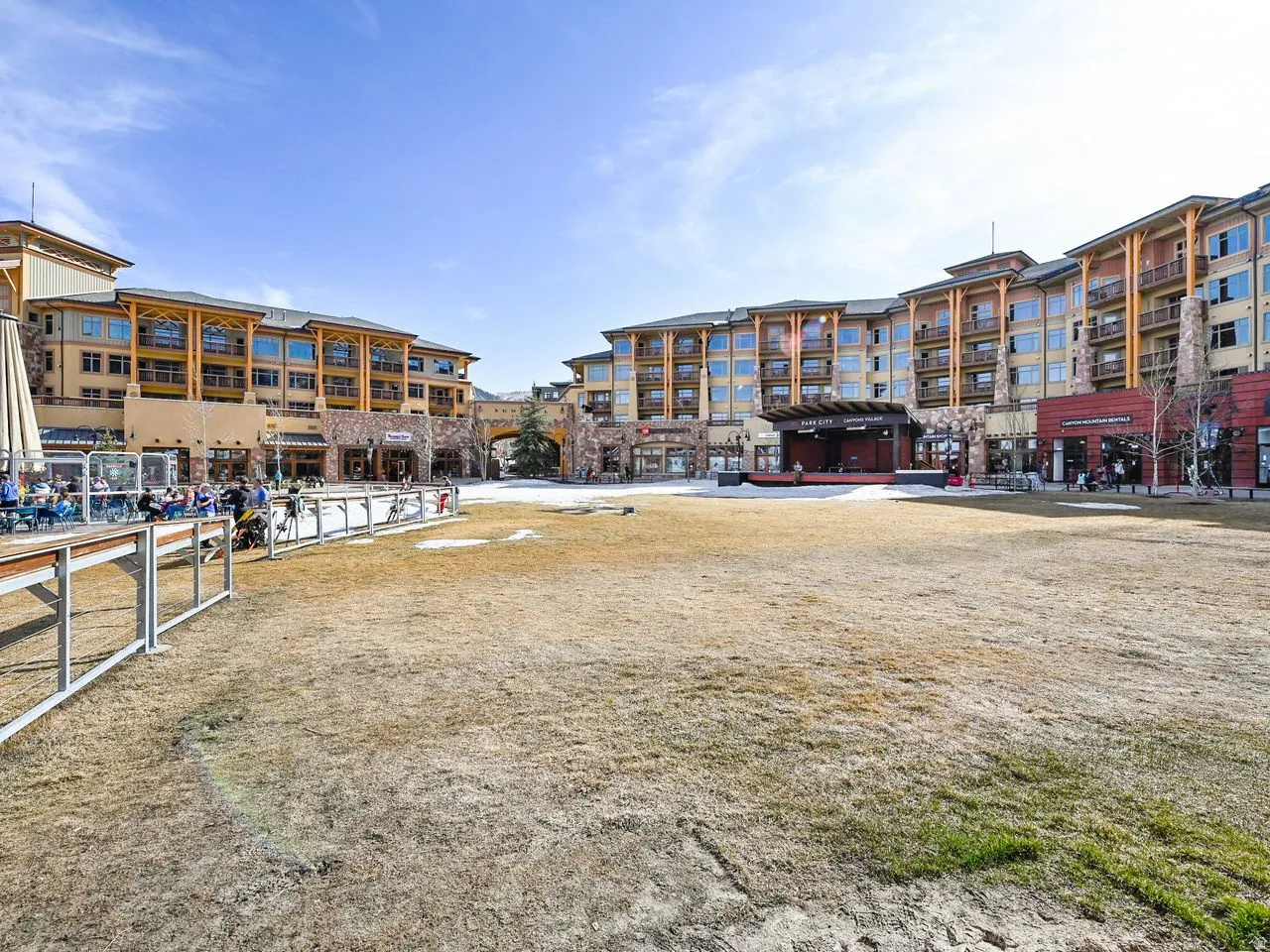 Expansive central plaza with a performance stage and surrounding multi-story buildings featuring balconies and commercial storefronts
