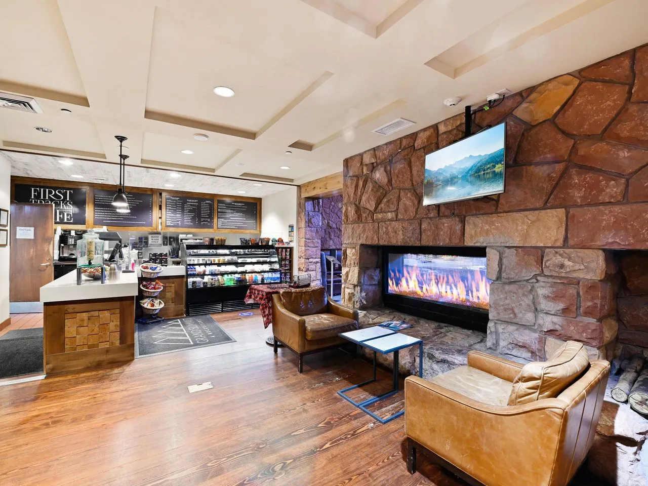 Inviting common area featuring wood-finish flooring, a stone-clad fireplace with a linear insert, and a built-in coffee bar