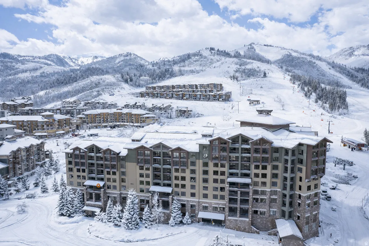 Multi-story building featuring stone and wood-finish exterior accents, multiple balconies, and a snow-covered alpine setting