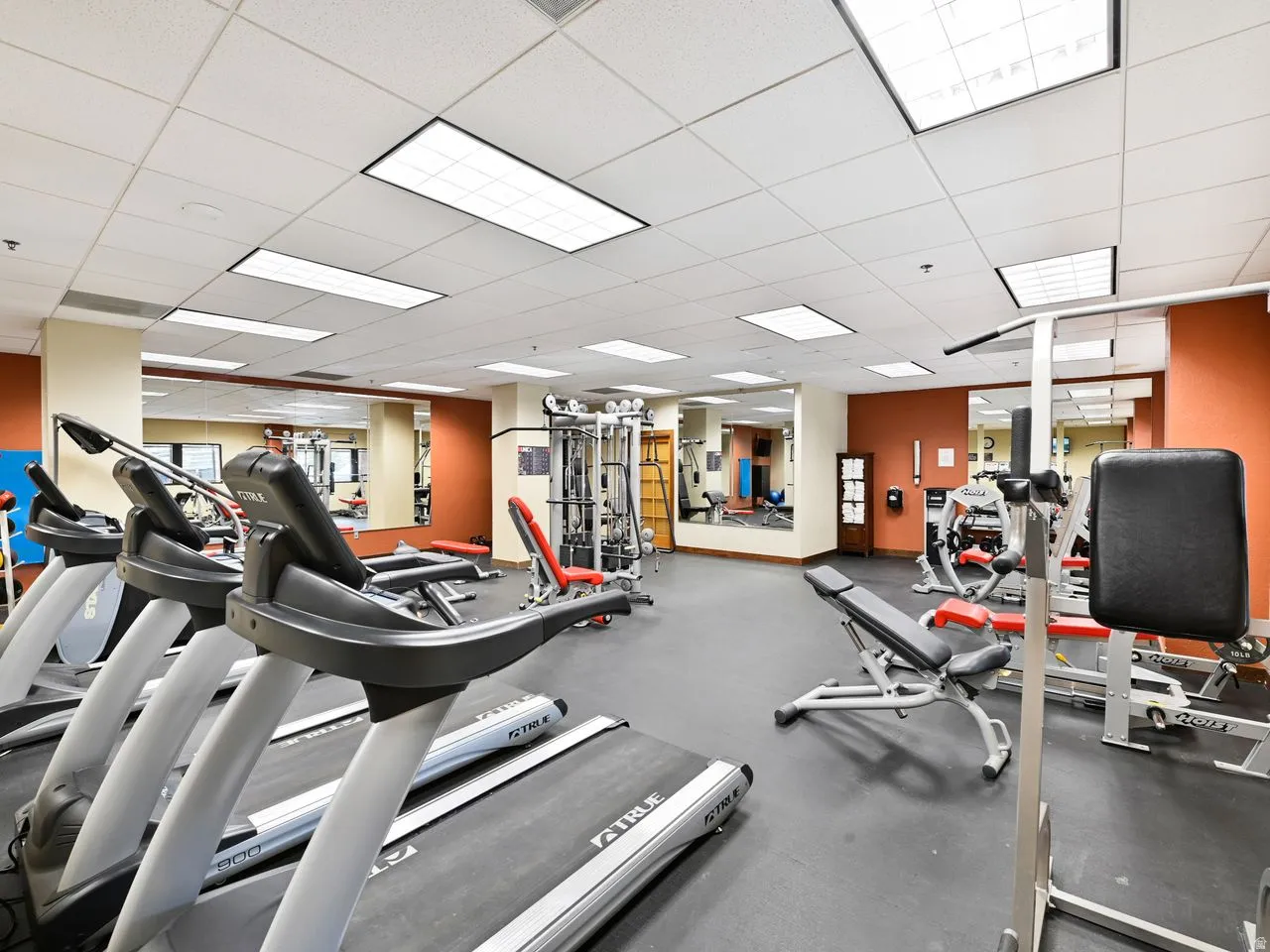 Fitness center featuring multiple treadmills, weight machines, and a mirrored wall