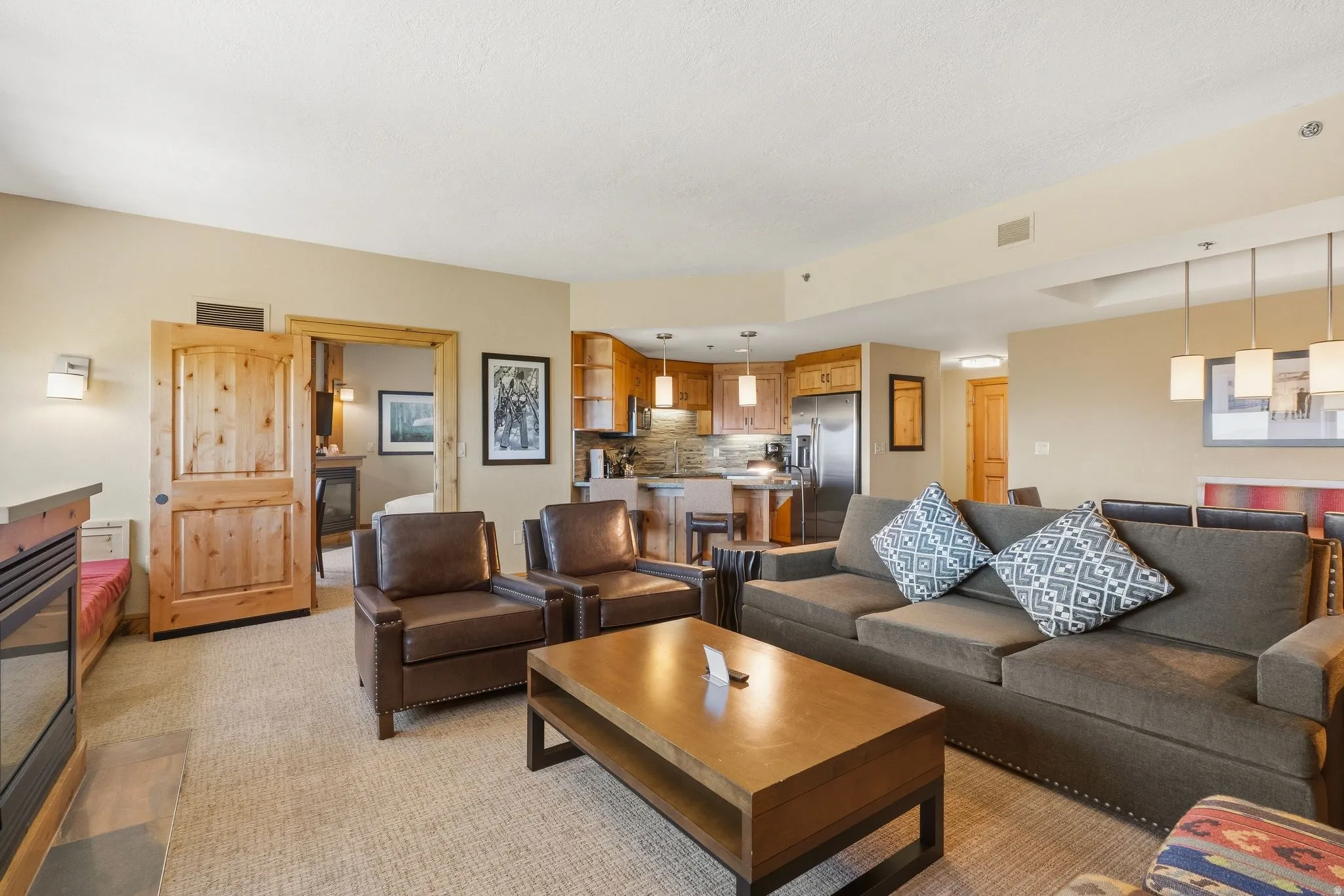Open-concept living area with a built-in electric fireplace, warm wood-finish cabinetry, and stainless steel appliances