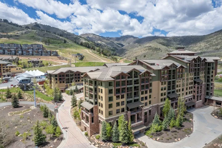Multi-story building featuring stone and wood-finish siding, a multi-gabled roofline, and numerous balconies