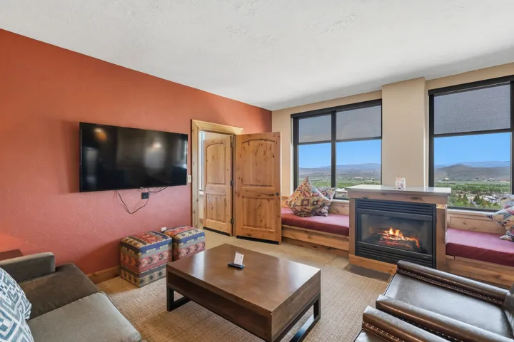 Living area featuring a built-in fireplace with a stone hearth, dual window benches, and two large windows with roller shades