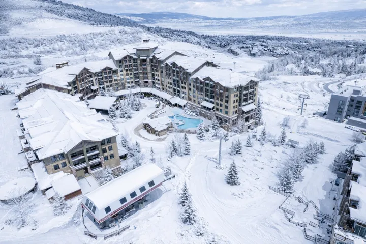 Expansive alpine resort showcasing a multi-story lodge with architectural details, multiple outdoor pools, and a dedicated ski lift station