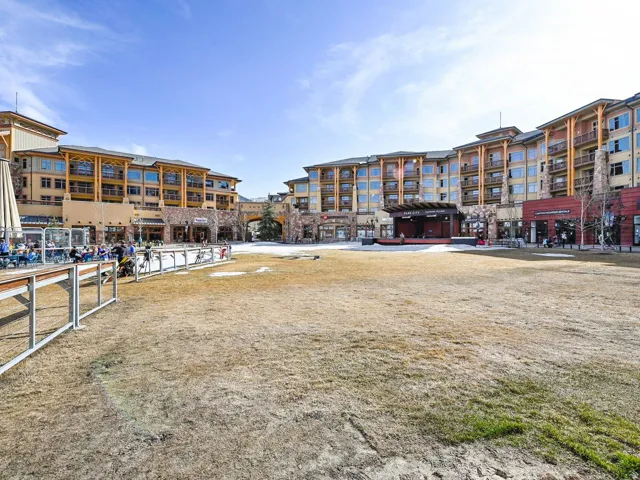 Expansive central plaza with a performance stage and surrounding multi-story buildings featuring balconies and commercial storefronts