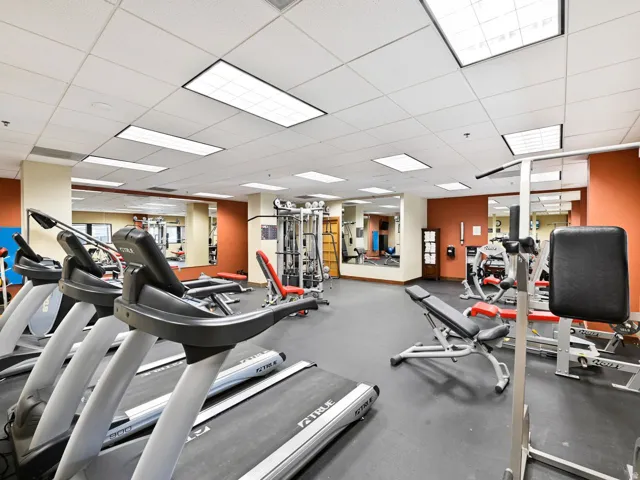 Fitness center featuring multiple treadmills, weight machines, and a mirrored wall