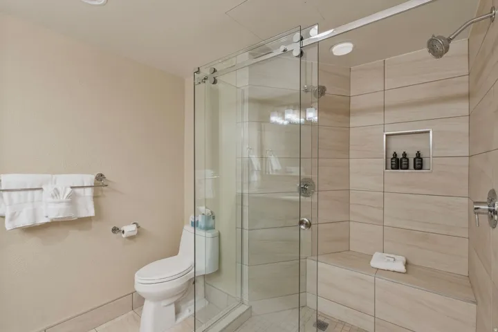 Glass-enclosed shower with a built-in bench, recessed niche, and contemporary tile surround