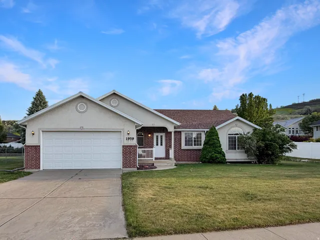 Ranch-style exterior featuring a two-car garage, brick accents, stucco siding, and a covered entry