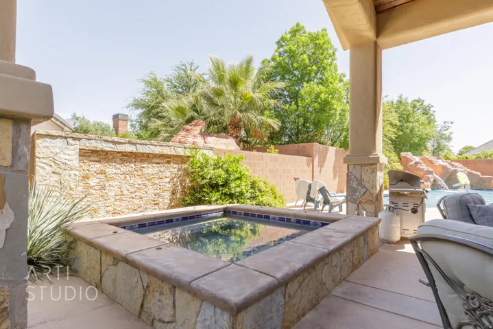 Outdoor spa with stone surround, complemented by a textured stone wall