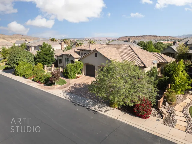Stucco exterior residence featuring a tile roof, an integrated two-car garage, and a paver driveway