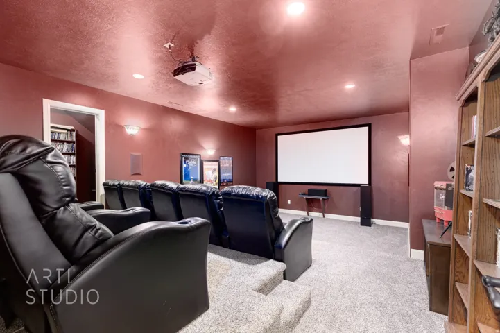 Dedicated home theater featuring a large projection screen, wall-mounted projector, and tiered seating