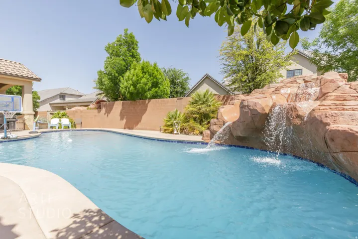 Inviting backyard oasis featuring a free-form swimming pool with a rock waterfall and integrated slide