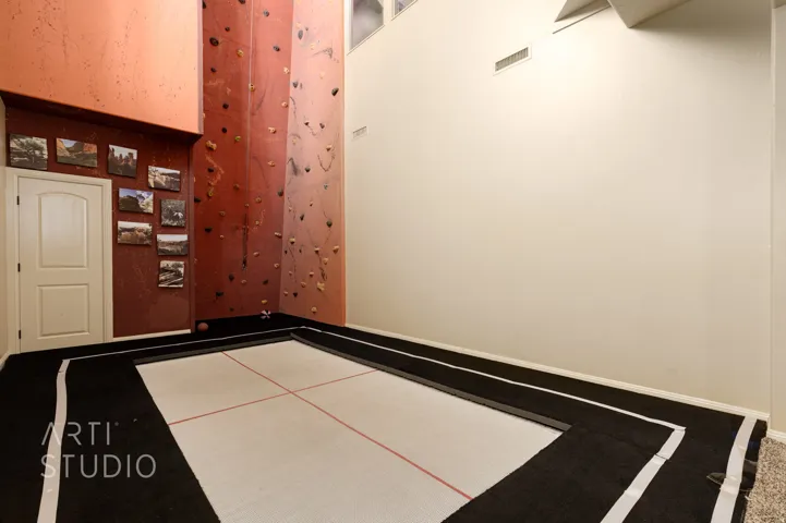 Interior space featuring a built-in trampoline and a tall climbing wall with various handholds