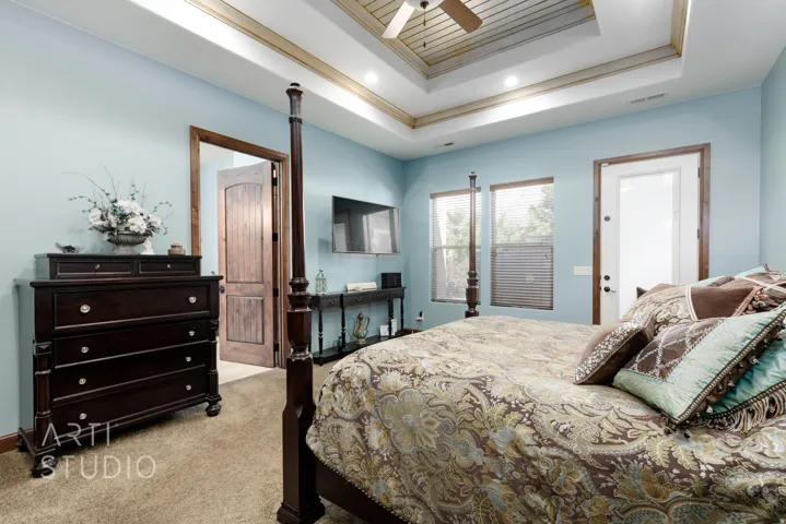 Bedroom featuring a tray ceiling with wood-finish details, recessed lighting, and a ceiling fan