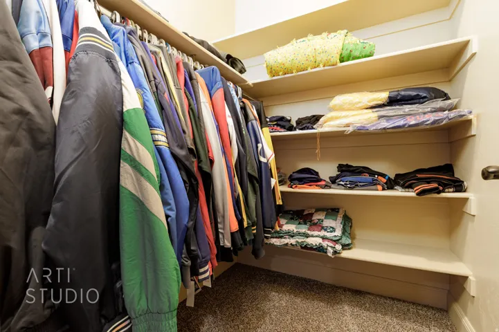 Organized closet space featuring a built-in hanging rod, multiple shelving units, and carpet flooring