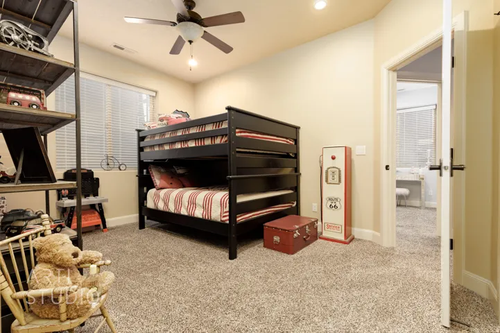 Carpeted room featuring a ceiling fan, window with horizontal blinds, and a white interior door with black hardware