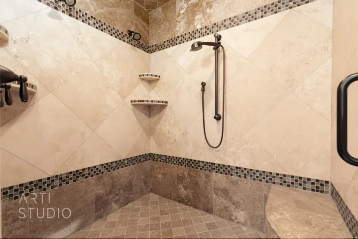Shower enclosure featuring diagonal-set tile walls, mosaic tile accents, a built-in bench, corner shelving, and oil-rubbed bronze fixtures