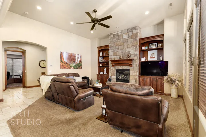 Spacious living area featuring a stacked stone fireplace with a wood mantle, built-in cabinetry, and recessed lighting
