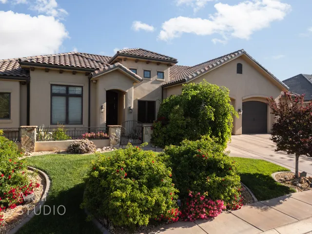 Stucco exterior residence featuring a tile roof, an arched entry, and a two-car garage