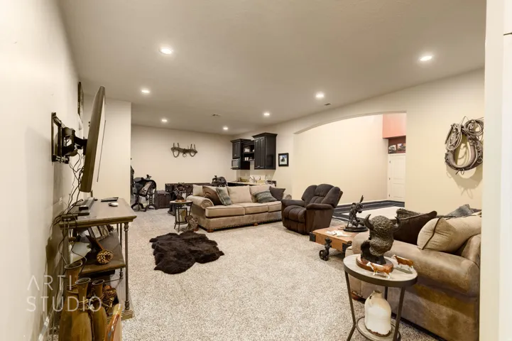 Spacious recreational room featuring recessed lighting, light-toned carpeting, and an arched entryway