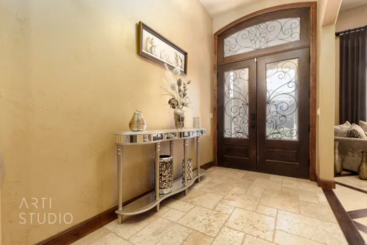 Double entry doors with decorative wrought iron inserts and an arched transom window