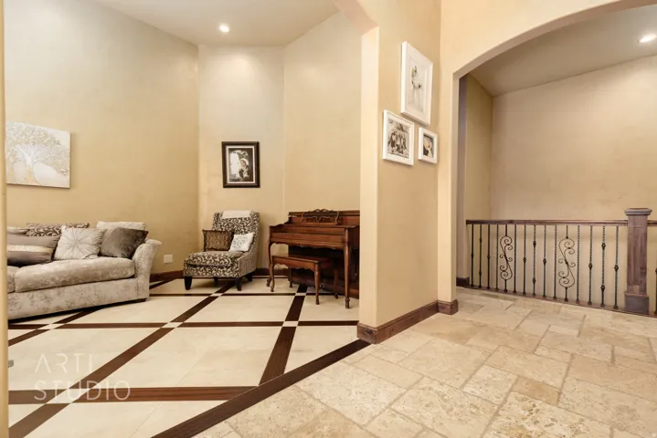 Spacious room with a distinctive tile floor featuring wood-finish inlay, recessed lighting, and a wrought iron banister with a wood-finish handrail