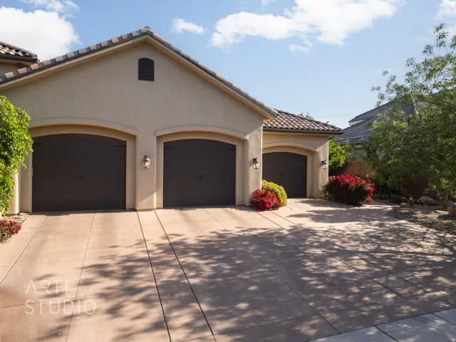 Stucco exterior featuring multiple garage bays with arched entrances