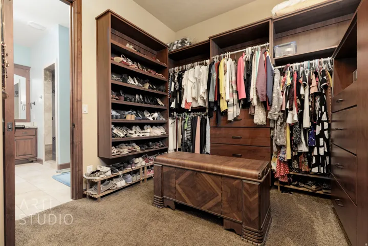 Built-in closet system featuring warm wood-finish cabinetry, extensive shelving, and multiple hanging rods