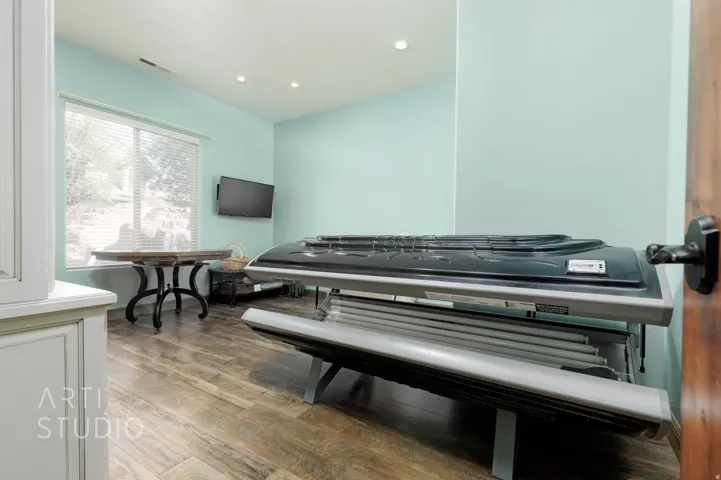 Spacious room featuring wood-finish flooring, recessed lighting, and a large window with blinds